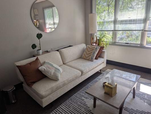 A photo of the office showing a couch and sunshine coming through the windows